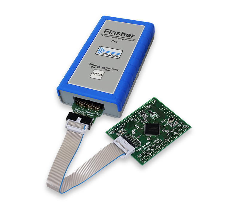 The image shows a programming device labeled "Flasher Pro" with a blue rubber casing. Attached is a green circuit board connected via a ribbon cable, used for programming and debugging electronic devices. The interface includes indicator lights and a programming button.